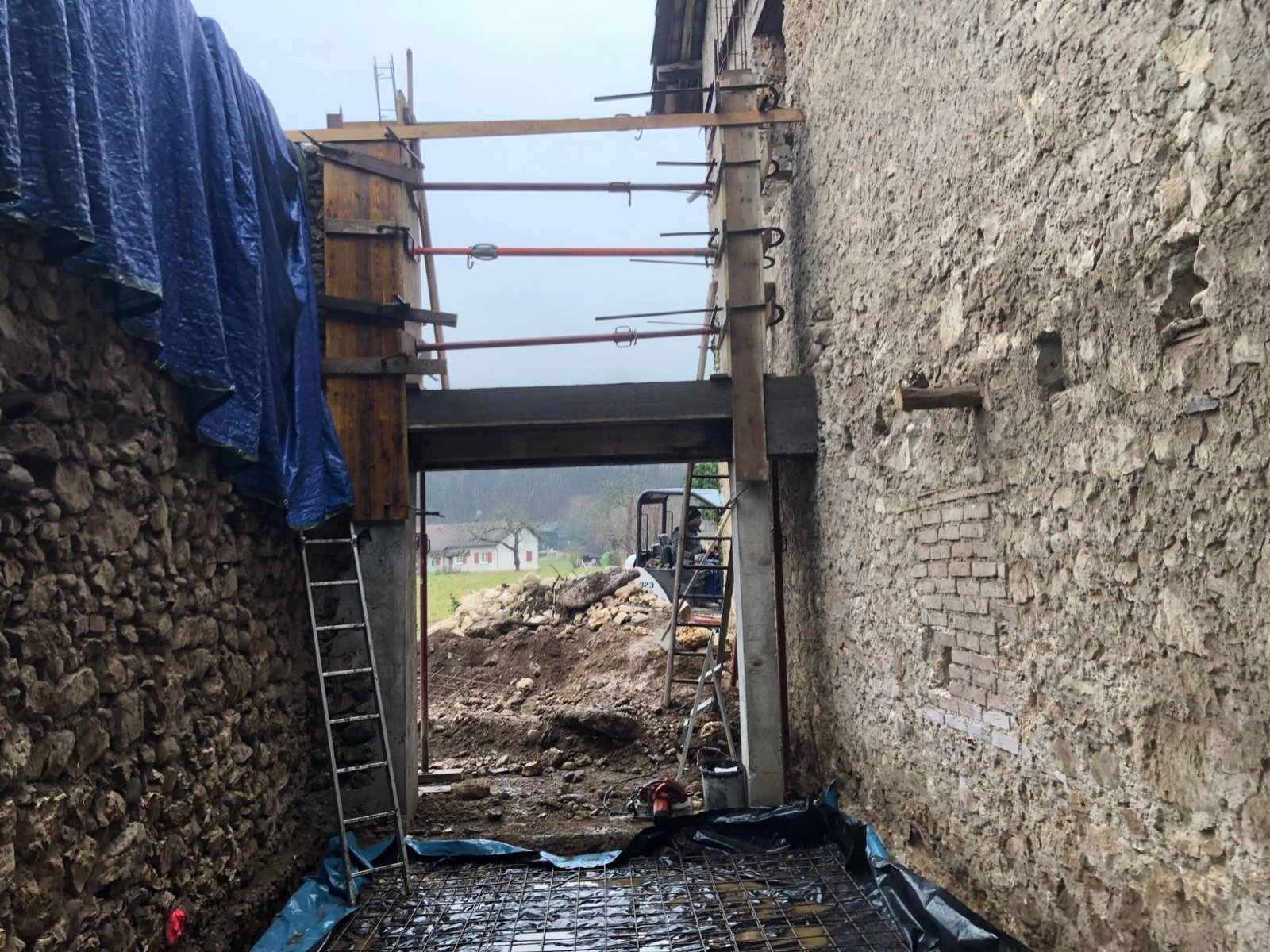 Pose d'un linteau béton entre deux murs en pierre